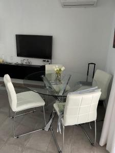 een glazen tafel met witte stoelen en een televisie bij Bungalow Santa Pola del Este in Gran Alacant