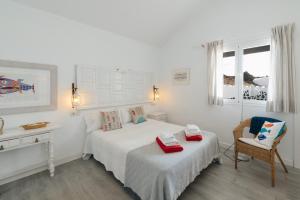 ein weißes Schlafzimmer mit einem Bett und einem Stuhl in der Unterkunft Casa Rural Caleton del Golfo in El Golfo