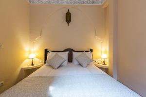 1 dormitorio con 1 cama blanca grande y 2 lámparas en Riad Amin, en Marrakech