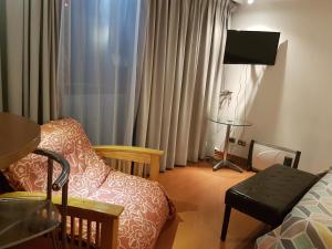 a room with a bed and a chair and a television at Departamento amplio en Suite, Costanera Center in Santiago