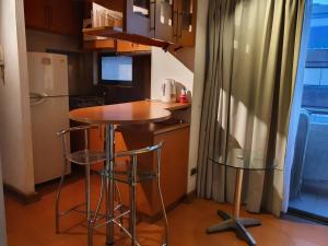 a small kitchen with a table and two stools at Departamento amplio en Suite, Costanera Center in Santiago