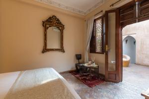 1 dormitorio con cama y espejo en la pared en Riad Amin, en Marrakech