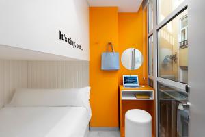 a bedroom with an orange accent wall and a bed at COEO Pod Hostel - Part of COEO Experience in Málaga