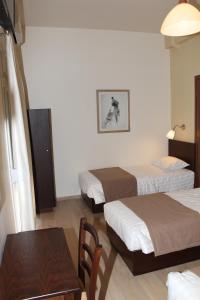 um quarto de hotel com duas camas e uma mesa em Rea Hotel em Heraclião