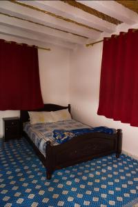 a bedroom with a bed and two red curtains at Hotel camping amtoudi in Id AÃ¯ssa