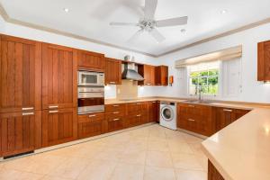 a large kitchen with wooden cabinets and a white appliance at Battaleys Mews lovely secure villa 5 minutes from Mullins beach in Saint Peter