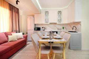 Il comprend une cuisine et un salon avec une table et un canapé. dans l'établissement Прекрасные апартаменты для путешествующих семей, à Almaty