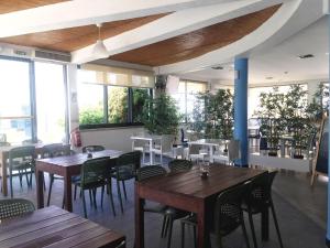 um restaurante com mesas e cadeiras de madeira e janelas em Clube Alvorférias em Alvor