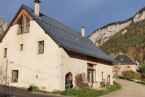 een wit huis met een zwart dak op een berg bij Gîte La Cochette in Corbel