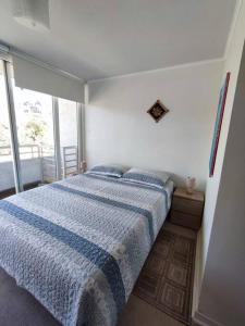 a bedroom with a bed and a large window at Departamento central Viña del Mar in Viña del Mar