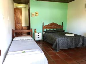 2 Betten in einem Zimmer mit grünen Wänden in der Unterkunft Aláfia Comandatuba in Una