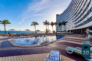 un hotel con piscina, palmeras y un edificio en Venha para a tranquilidade à beira-mar em Salvador, en Salvador