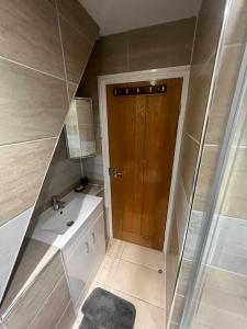 a bathroom with a sink and a wooden door at Hampden Rd N8,Studio Flat in London