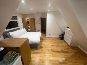 Schlafzimmer mit einem weißen Bett und Holzboden in der Unterkunft Hampden Rd N8,Studio Flat in London