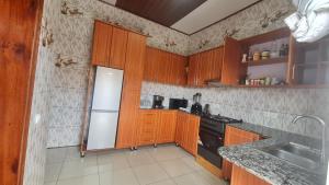 a kitchen with wooden cabinets and a white refrigerator at CLEMENT MOTEL in Rutsiro