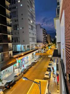 a city street at night with cars parked on the street at Rivadavia Apart in Mar del Plata