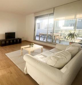 ein Wohnzimmer mit einem weißen Sofa und einem großen Fenster in der Unterkunft Beach & Culture Barcelona Port Forum Penthouse Apartment in Barcelona