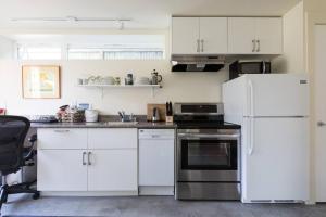 una cocina con armarios blancos y electrodomésticos blancos en LEED Platinum Green Home Getaway, en Seattle