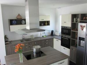 a kitchen with a refrigerator and a table with flowers on it at Villa Étel, 5 pièces, 8 personnes - FR-1-479-15 in Étel