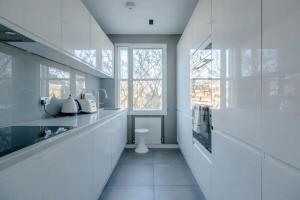 a white kitchen with a sink and a window at Modern and Luxurious 2 Bedroom Flat - Barons Court in London