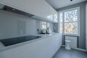 a white kitchen with a sink and a window at Modern and Luxurious 2 Bedroom Flat - Barons Court in London