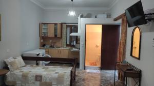 TRADITIONAL HOUSE ALEPIS IN AREOPOLIS في أريوبوليس: غرفة معيشة مع أريكة وتلفزيون ومطبخ