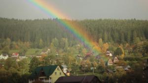 a rainbow over a town with a forest at Petrovmotopunkt in Yaremche