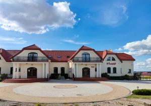 a large white building with a red roof at Hotel Viwaldi in Baruchowo