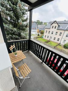 d'un balcon avec une chaise en bois et une table. dans l'établissement Cosy Apartment I 5Beds I Near VW, à Glauchau