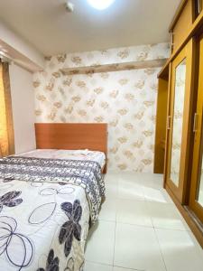 una camera con un letto con una parete decorata con fiori di Sewa Apartemen Kalibata City by The Best a Giacarta