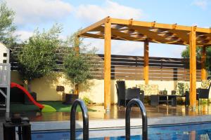 a swimming pool with a wooden pergola next to a swimming pool at The Blue Leaf Family Villa in Gennadi