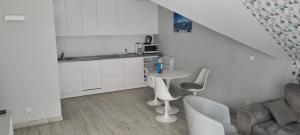 eine weiße Küche mit weißen Stühlen und einem Tisch in der Unterkunft Apartament Czarna Gora B39 in Heudorf