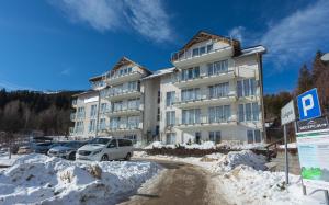 a large white building with cars parked in the snow at Apartament Czarna Gora B39 in Sienna +5 photos