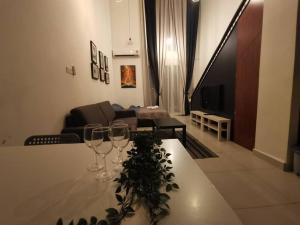 a table with wine glasses and a living room at Teddy's Homestay in Cyberjaya