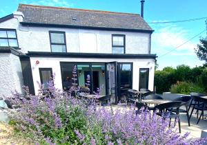 a house with tables and chairs and purple flowers at The Roost on Rock Road in Barry