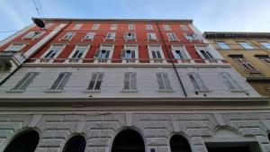 un edificio alto de color rojo con ventanas en la parte superior de un edificio en Palazzo Crispi - Boutique Apartment, en Trieste