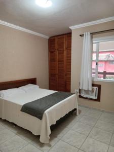 une chambre avec un grand lit et une fenêtre dans l'établissement FLAT AMARILIS RIVIERA DE SÃO LOURENÇO, à Bertioga