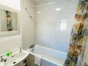 un bagno bianco con vasca e lavandino di St Albans Village Studios by DC London Rooms a Londra