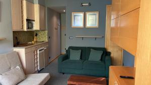 a living room with a green couch in a kitchen at Tobazo Candanchú pie de pista in Candanchú