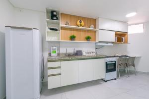 cocina con armarios blancos y nevera en Studio Encantador - Garagem - Piscina na Cobertura, en João Pessoa