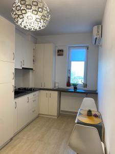 een keuken met witte kasten en een tafel en stoelen bij Q Apartament Loft place near Palas Mall in Iaşi