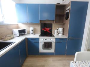 a kitchen with blue cabinets and a red object on the stove at Bénodet : Superbe T2 rénové à 100m de la plage, parking inclus - FR-1-481-90 in Bénodet