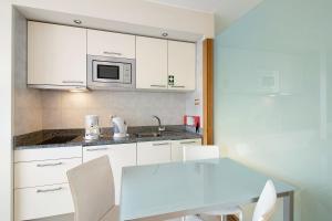 a kitchen with white cabinets and a table and a microwave at Dfm Happy Days C - Funchal in Funchal