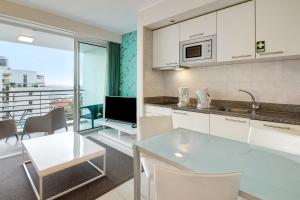 uma cozinha com armários brancos e uma mesa e cadeiras em Dfm Happy Days C - Funchal em Funchal
