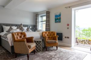 a bedroom with a large bed and two chairs at Western Isles Hotel in Tobermory