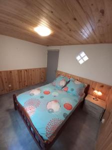 uma pequena cama num quarto com tecto em madeira em Les Durantas em Cilaos