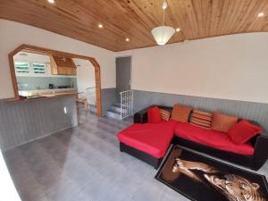 een woonkamer met een rode bank en een keuken bij Les Durantas in Cilaos