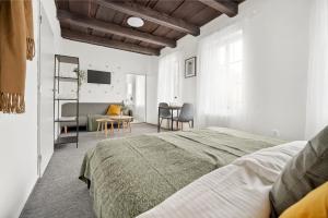 a white bedroom with a bed and a table at Penzion Village Peace #29 by Goodnite cz - U Libušky in Brno