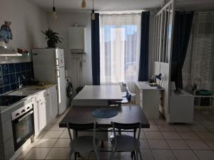 een keuken met een tafel en stoelen en een koelkast bij Ma petite escale in Romans-sur-Isère