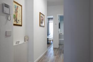 Habitación con paredes blancas y pasillo con pinturas. en A Due Passi - Guest House, en Santo Stefano di Camastra